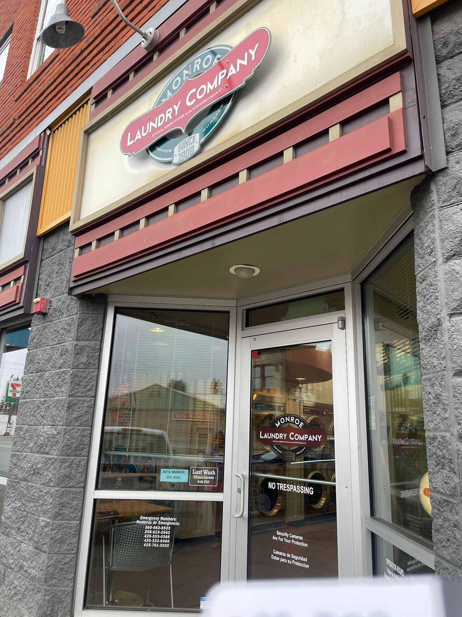 The Monroe Laundry Company storefront: a red awning and oval sign above a glass door, set into a brick and stone facade on Main Street